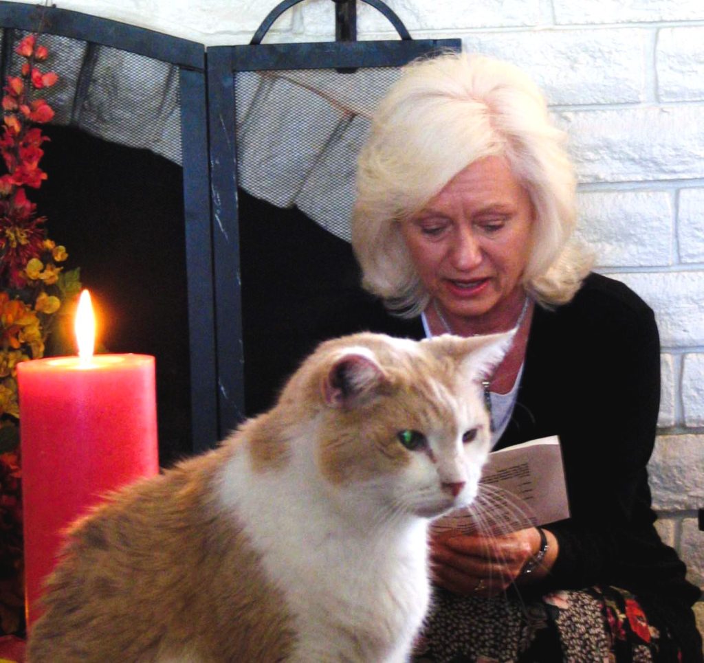 Gail Pope reading a book to a blind old orange cat