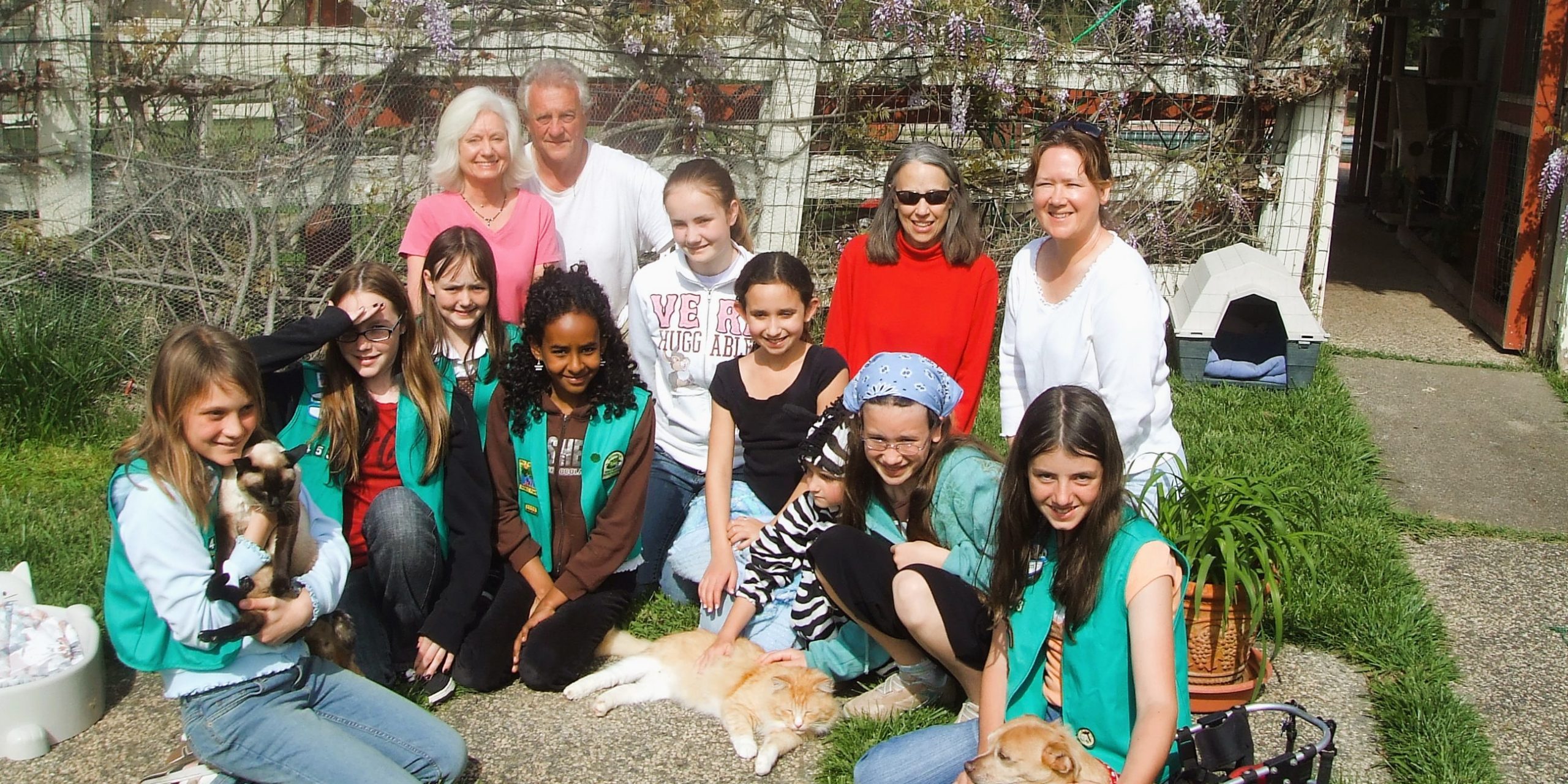 Gail and Richard with a group of kids surrounded by animals that suffer chronic conditions
